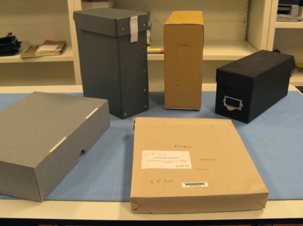 De gauche à droite : boîte Klug, boîte Cauchard, boîte SECAN, boîte sur mesure ; au centre : pochette de conservation avec ses différentes mentions. Cliché INHA